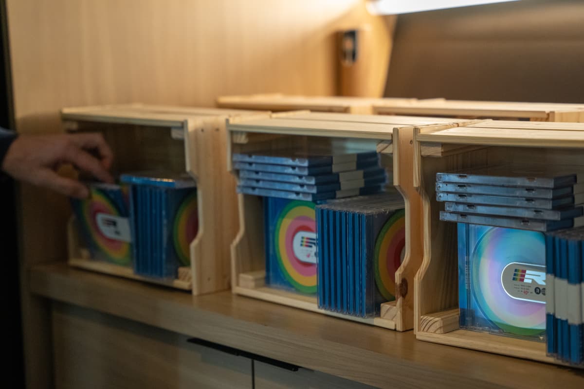 Hand reaching for a Remix Jam CD from 1 of 3 wooden boxes